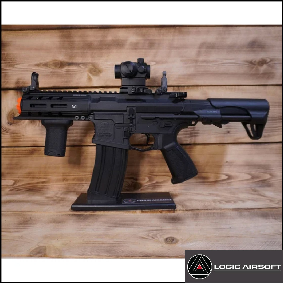 Black airsoft AEG rifle with scope, on stand, full view